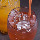 Glass of orange beverage with ice cubes.